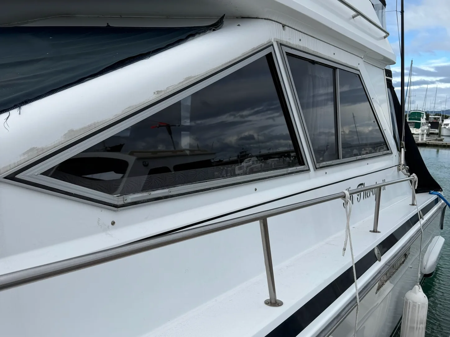 A row of cabin windows on a launch moored at the marina