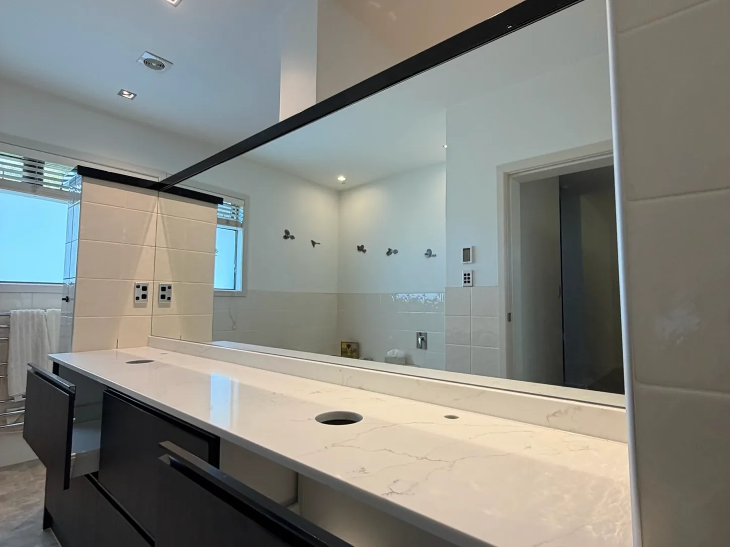 Mirror fitted the width of a vanity with dark cabinetry