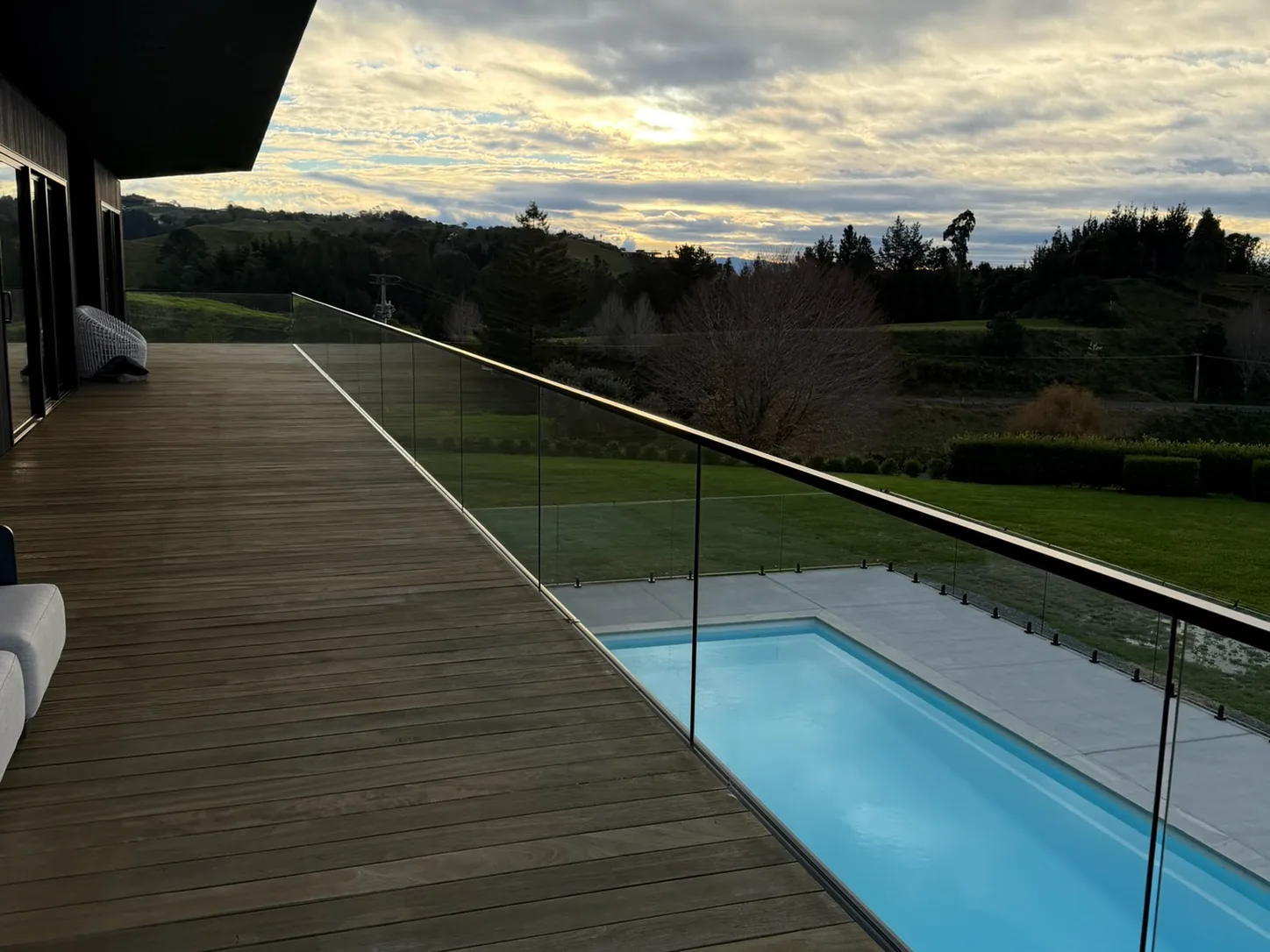 Frameless glass pool fencing along a timber deck at dusk
