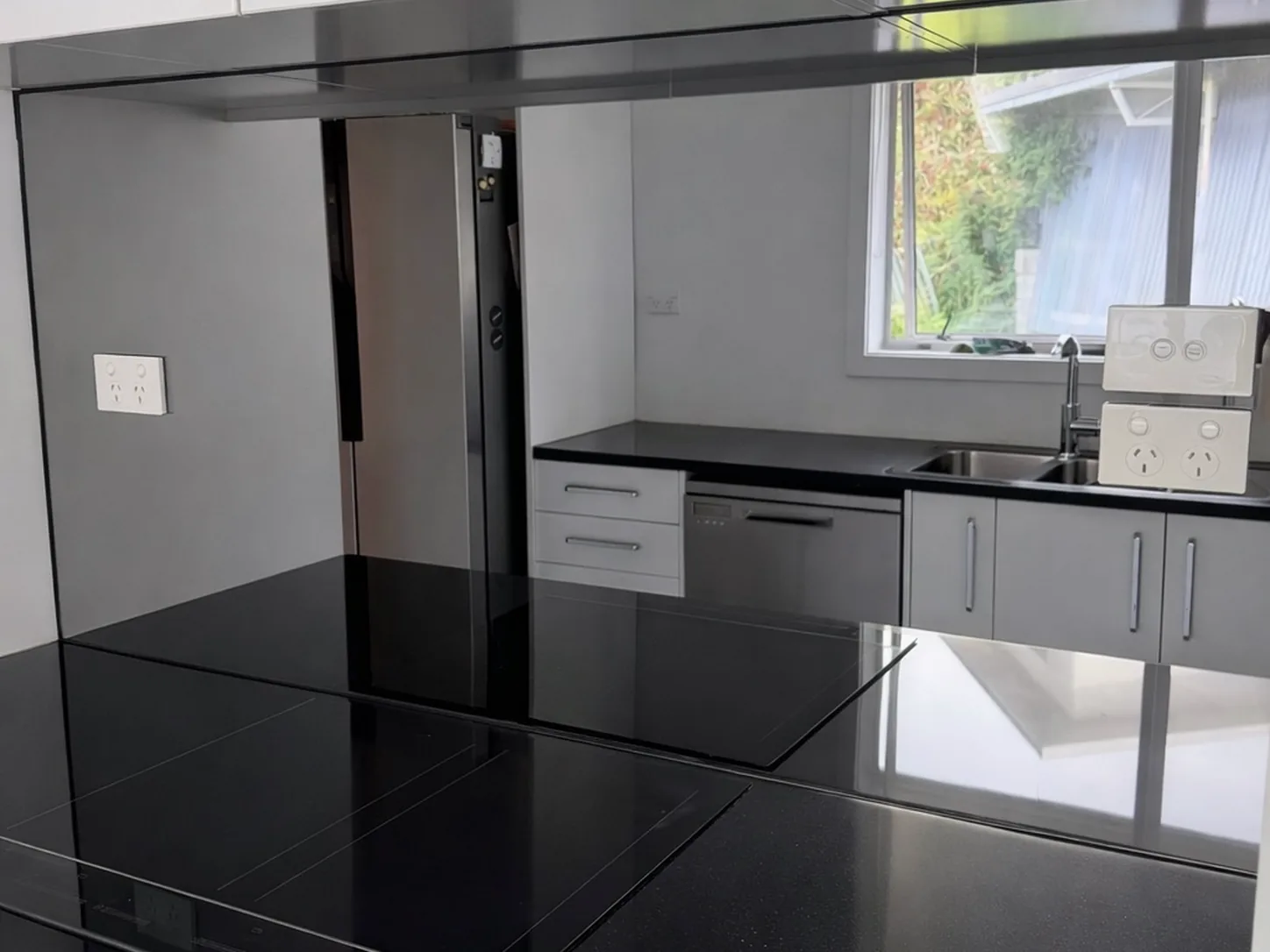 Black gloss glass splashback running the length of a kitchen bench